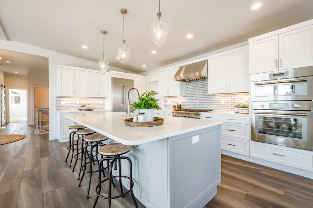 bright open concept kitchen in white with long counter eating space dining room and large windows